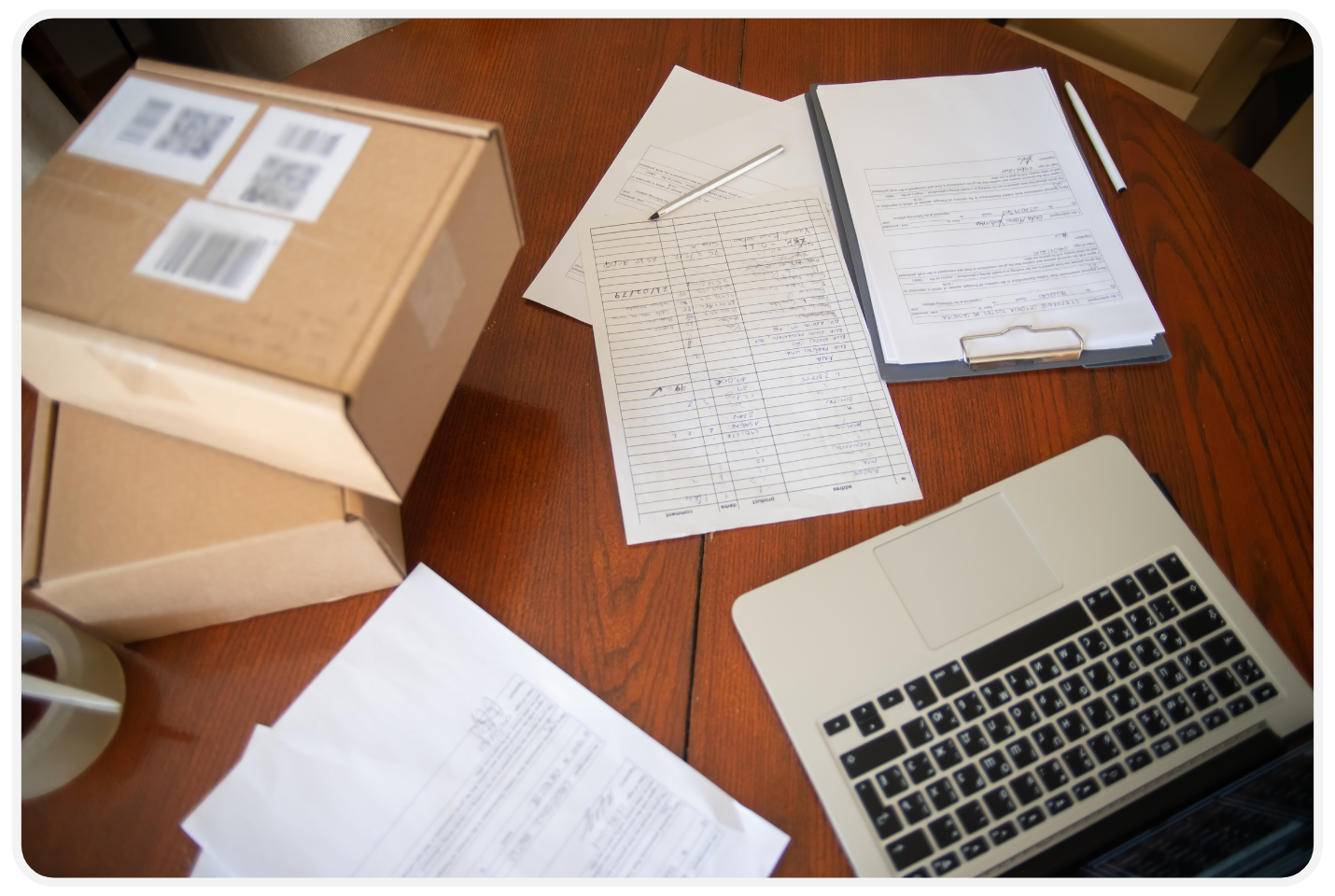 Shipping documents, labeled packages, and a laptop prepared for online freight shipment document submission.